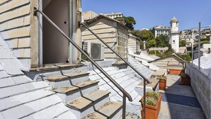 A set of stone steps leading to a building entrance, with a metal railing and potted plants. - Garibaldi Attic by Wonderful Italy (Genoa)