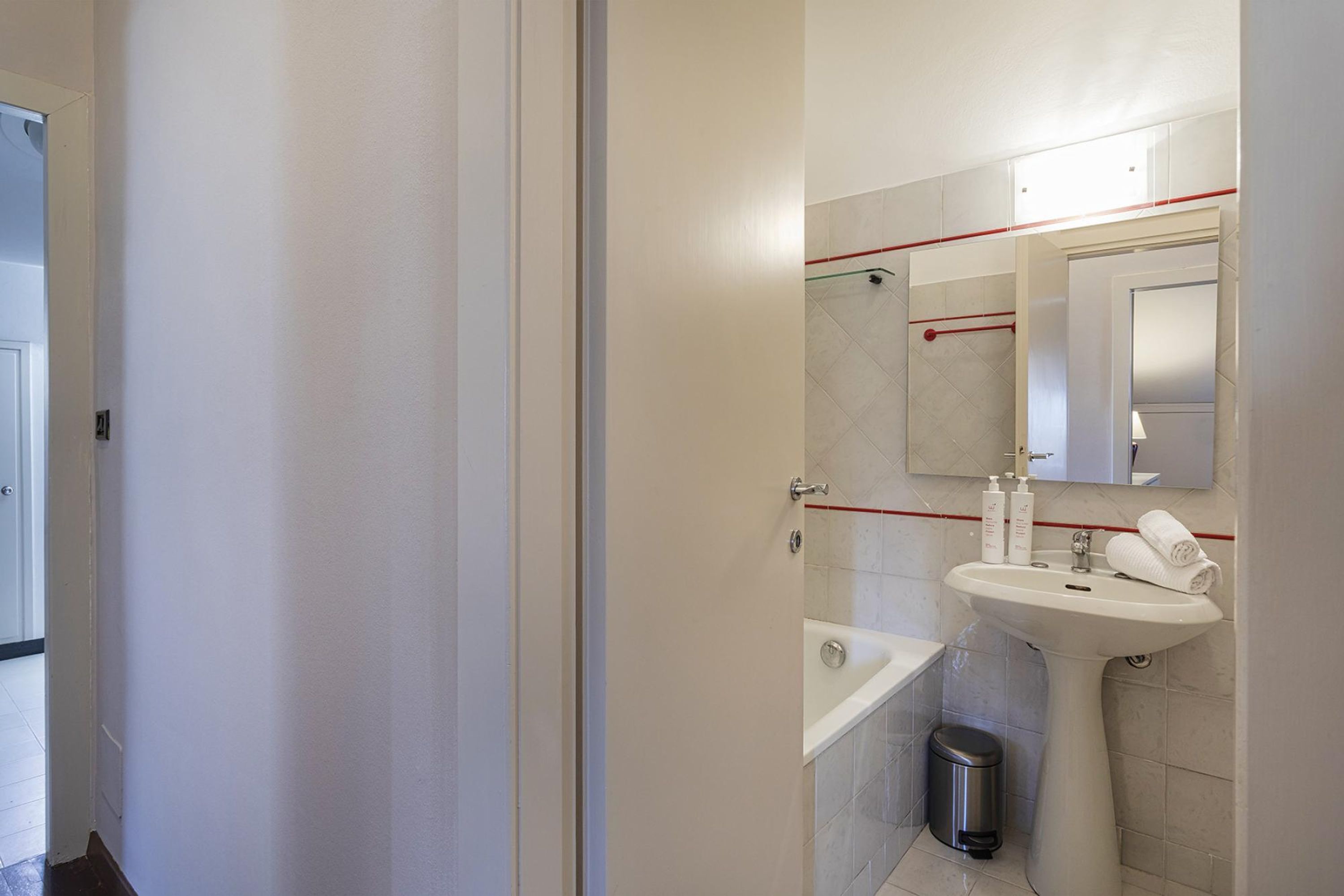 A bathroom with a white sink, mirror, and tiled walls.