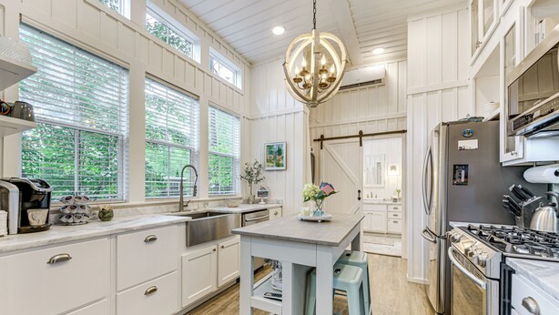 A kitchen with white cabinetry, a central island, stainless steel appliances, and large windows. - Highlands Vacation Rental - Walk to Main St! (Highlands)