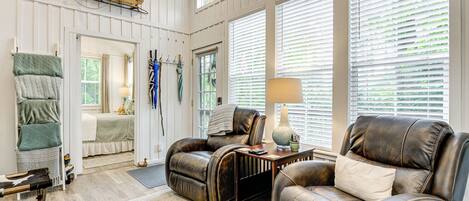 A spacious living room with leather sofas, a wooden coffee table, and a large window with blinds.