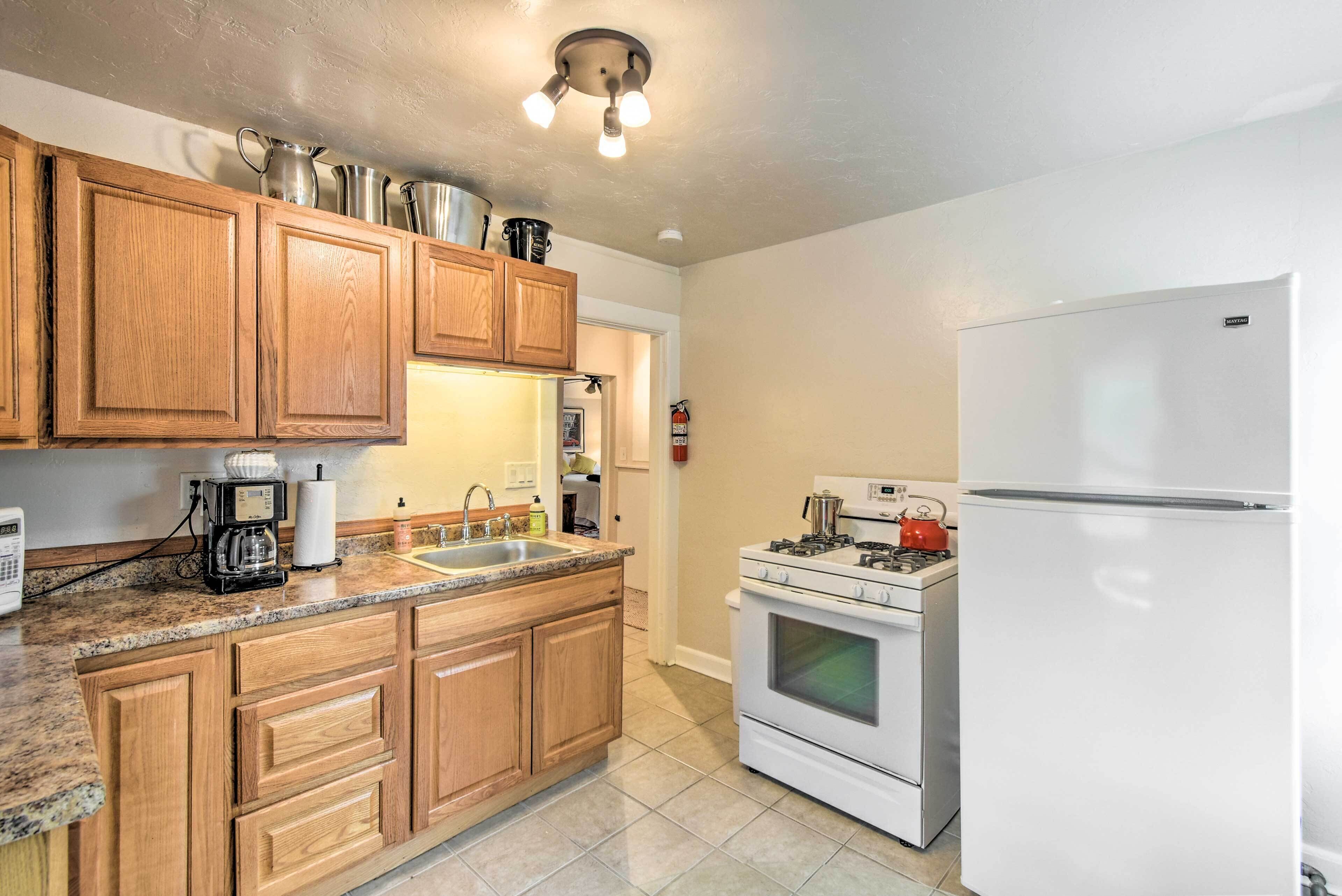A kitchen with wooden cabinets, a white refrigerator, a stove, and a coffee maker.