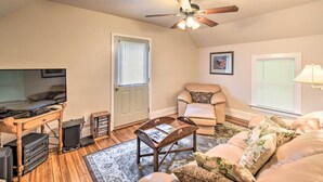 Un salon chaleureux avec un ventilateur de plafond, un canapé, un fauteuil et une table basse.