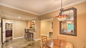 A dining room with a wooden table and chairs, a chandelier, and a large mirror on the wall.