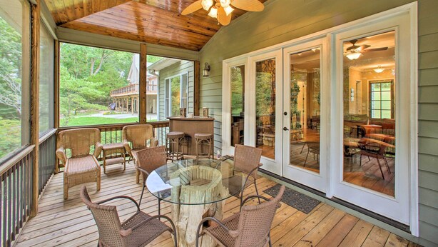A covered porch with wicker furniture, a glass table, and a ceiling fan.