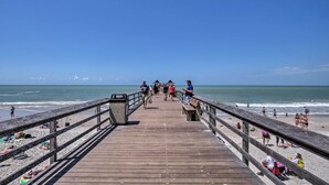 A wooden pier leading to a beach with people walking and sitting. - Luxe Naples Escape: Walk to Beach & Downtown! (Naples)