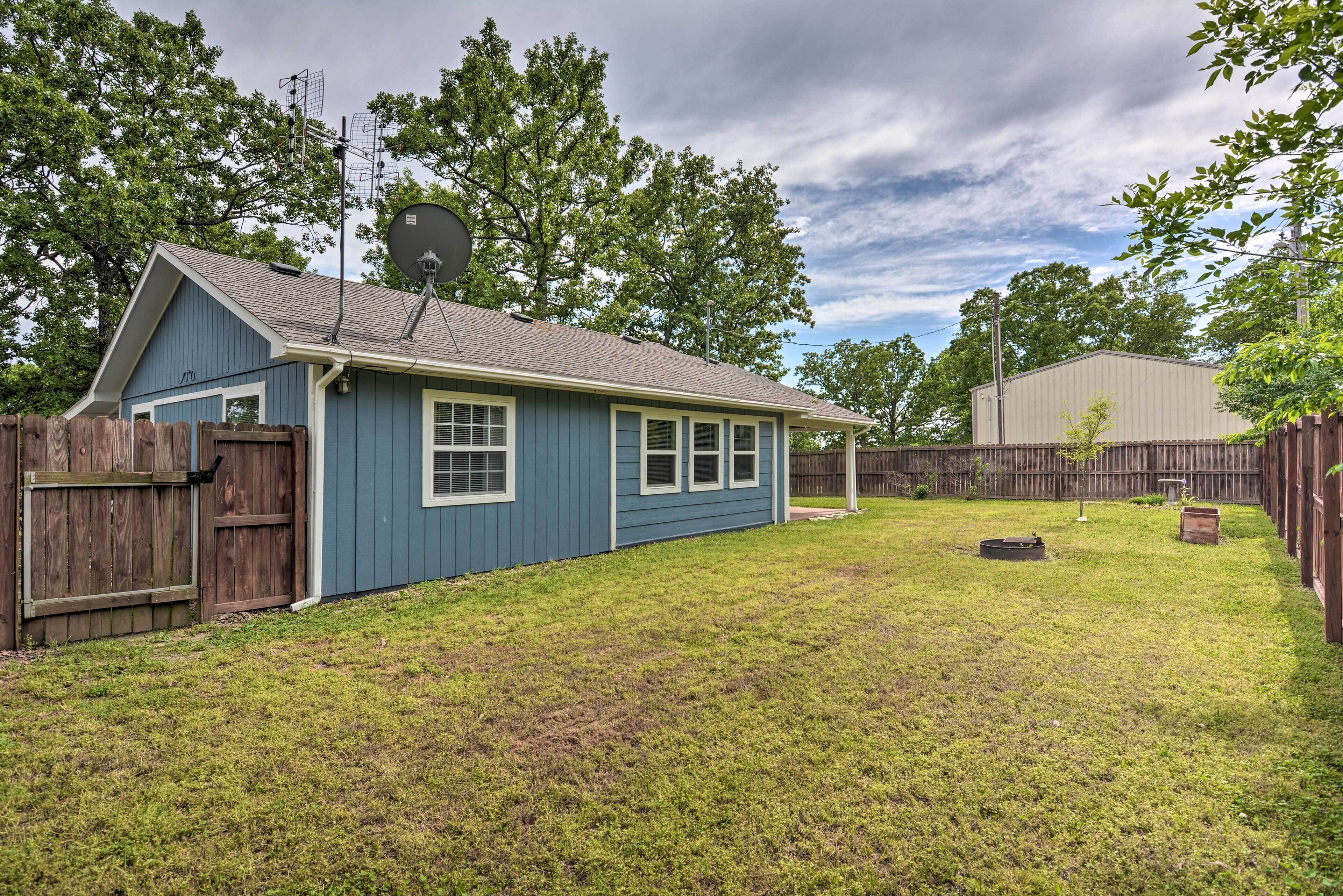 A residential backyard with a blue house, a wooden fence, and a satellite dish.