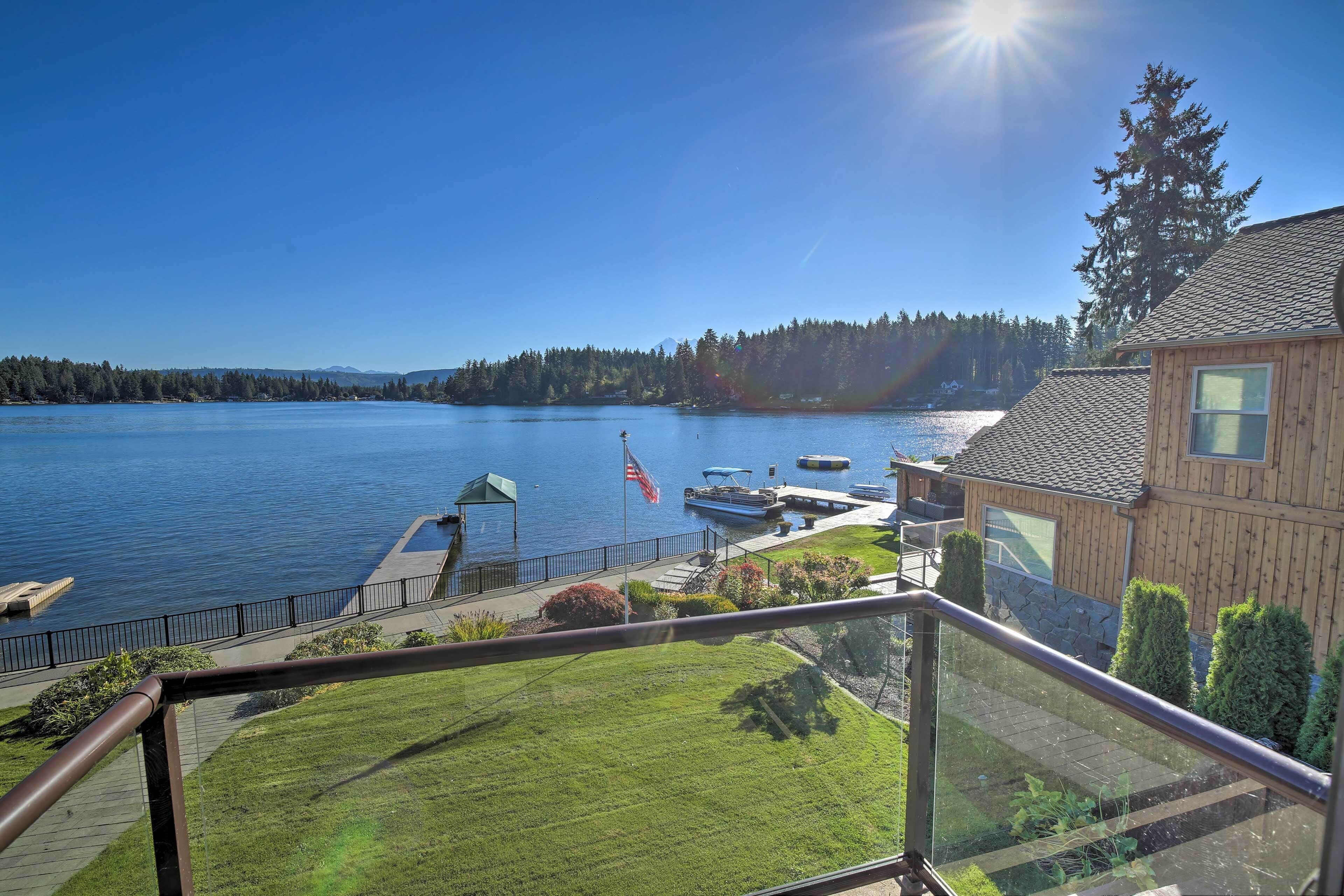 A lakeside property with a wooden cabin, dock with boats, and a clear view of the lake and forested hills.