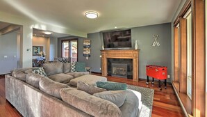 A spacious living room with a sectional sofa, a fireplace, a television, and a foosball table. - Lake Lovers Oasis: Hot Tub & Mt Rainier View! (Eatonville)