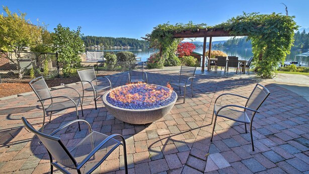 A patio with a fire pit, outdoor seating, and a view of a lake. - Lake Lovers Oasis: Hot Tub & Mt Rainier View! (Eatonville)
