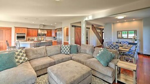 A spacious living area with a large sectional sofa, a dining table with chairs, and a kitchen in the background. - Lake Lovers Oasis: Hot Tub & Mt Rainier View! (Eatonville)