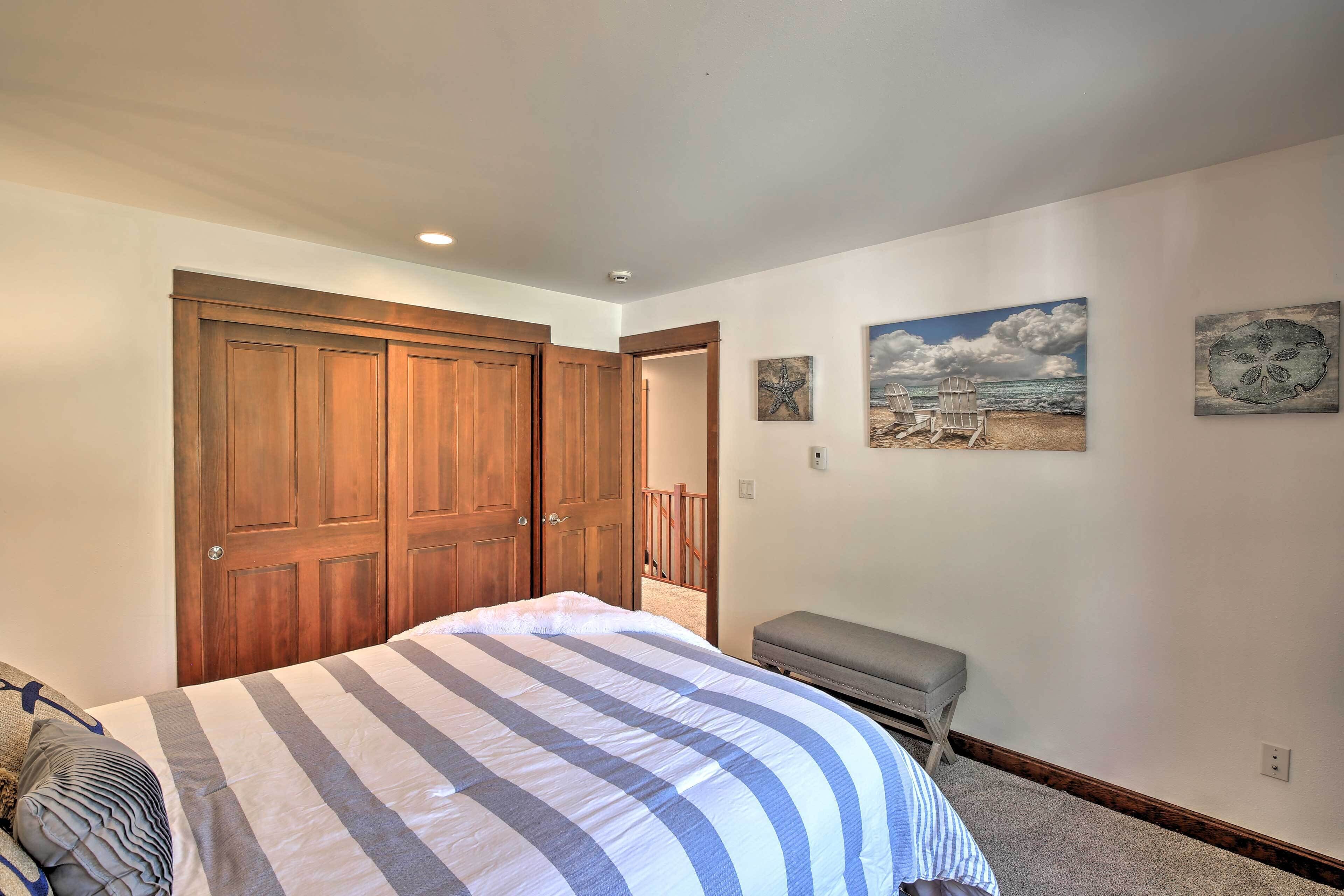 A bedroom with a large bed, wooden wardrobe, and artwork on the wall.