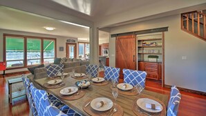 A dining area with a large wooden table set for six, surrounded by blue patterned chairs. - Lake Lovers Oasis: Hot Tub & Mt Rainier View! (Eatonville)