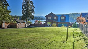 A residential property with a large lawn, a wooden house, and a view of a lake and mountains. - Lake Lovers Oasis: Hot Tub & Mt Rainier View! (Eatonville)
