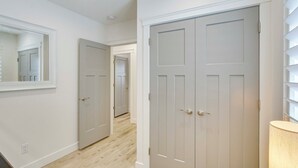 A hallway with white walls, a wooden floor, and a double door with a mirror above it. - Logan Area Home Near Willard Bay State Park! (Brigham City)