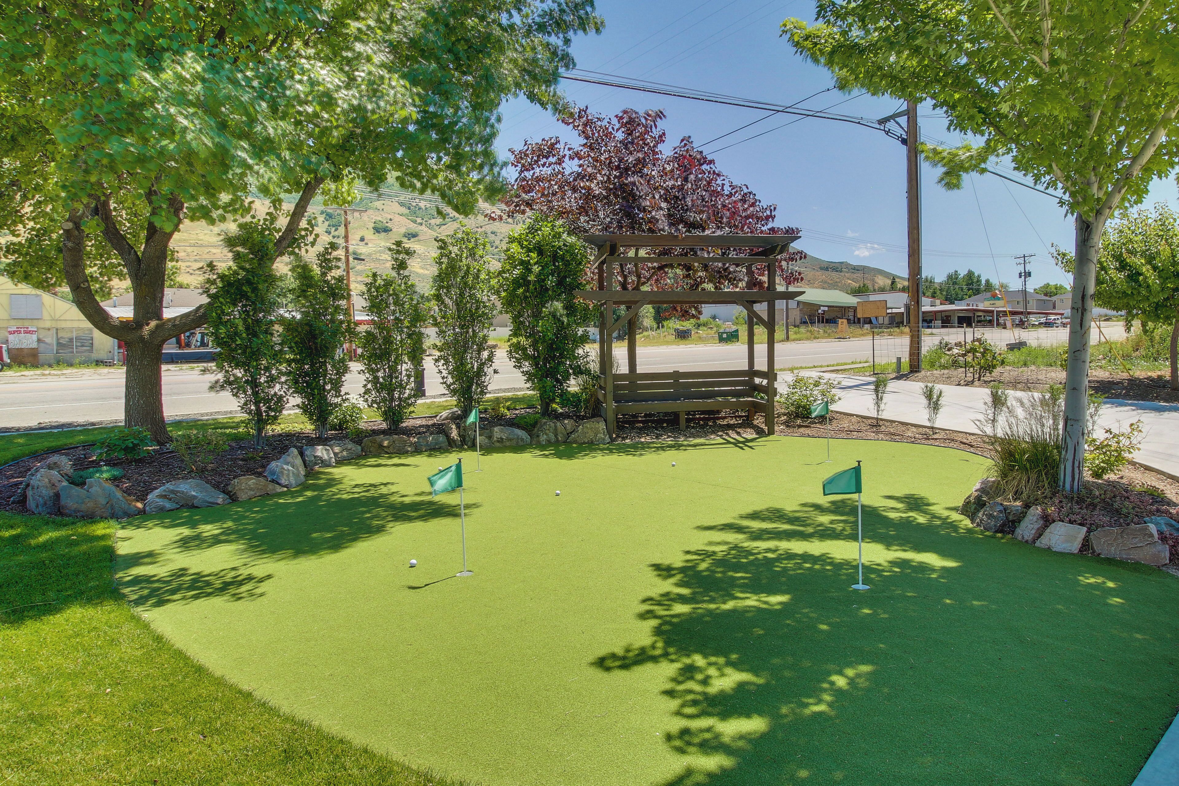 A miniature golf course with a wooden gazebo, a well-maintained lawn, and a clear sky.