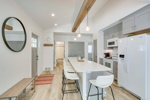 Una cocina moderna con una isla central, armarios blancos y un espejo grande.