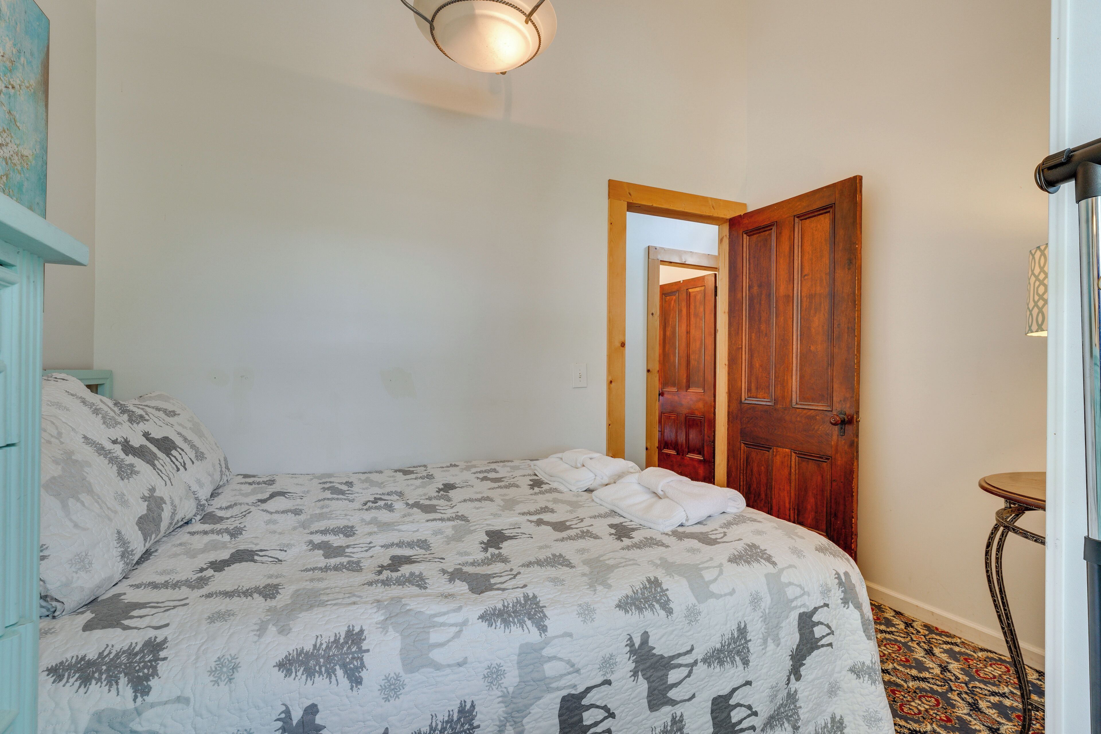 Ein Schlafzimmer mit einem Bett, einer Holztür und einem kleinen Tisch.