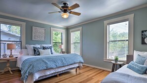 A bedroom with a bed, a ceiling fan, and large windows.