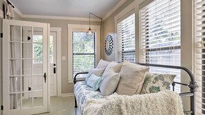 A room with a bed, a white door, and windows with blinds.