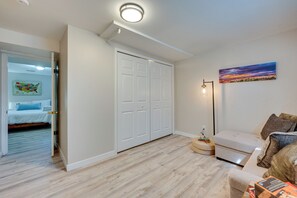 Une pièce comprenant un lit, une armoire blanche, un canapé et un tableau accroché au mur.