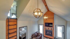 Un dormitorio estilo loft con cama en entrepiso, un sofá de cuero, chimenea y zona de comedor.