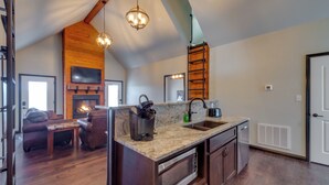 Una cocina amplia con una isla grande, detalles de madera, una chimenea y un área de comedor con un sofá.
