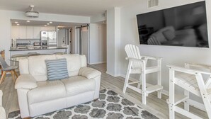 A modern living room with a white leather sofa, a patterned rug, and a TV mounted on the wall.