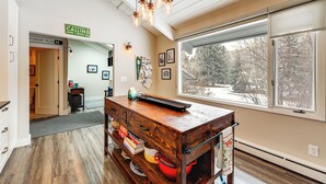 A kitchen with a wooden island, a window with a view of trees, and a sign on the wall. - Modern Mountain Escape on Golf Course w/ Hot Tub! (Avon)