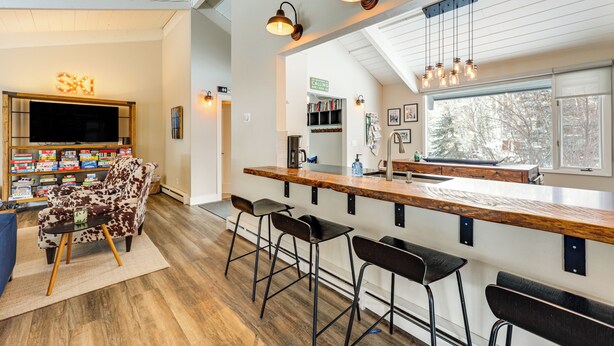A modern kitchen with a wooden countertop, bar stools, and pendant lighting. - Modern Mountain Escape on Golf Course w/ Hot Tub! (Avon)