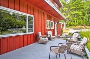 A red house with a porch, wicker chairs, and a table.