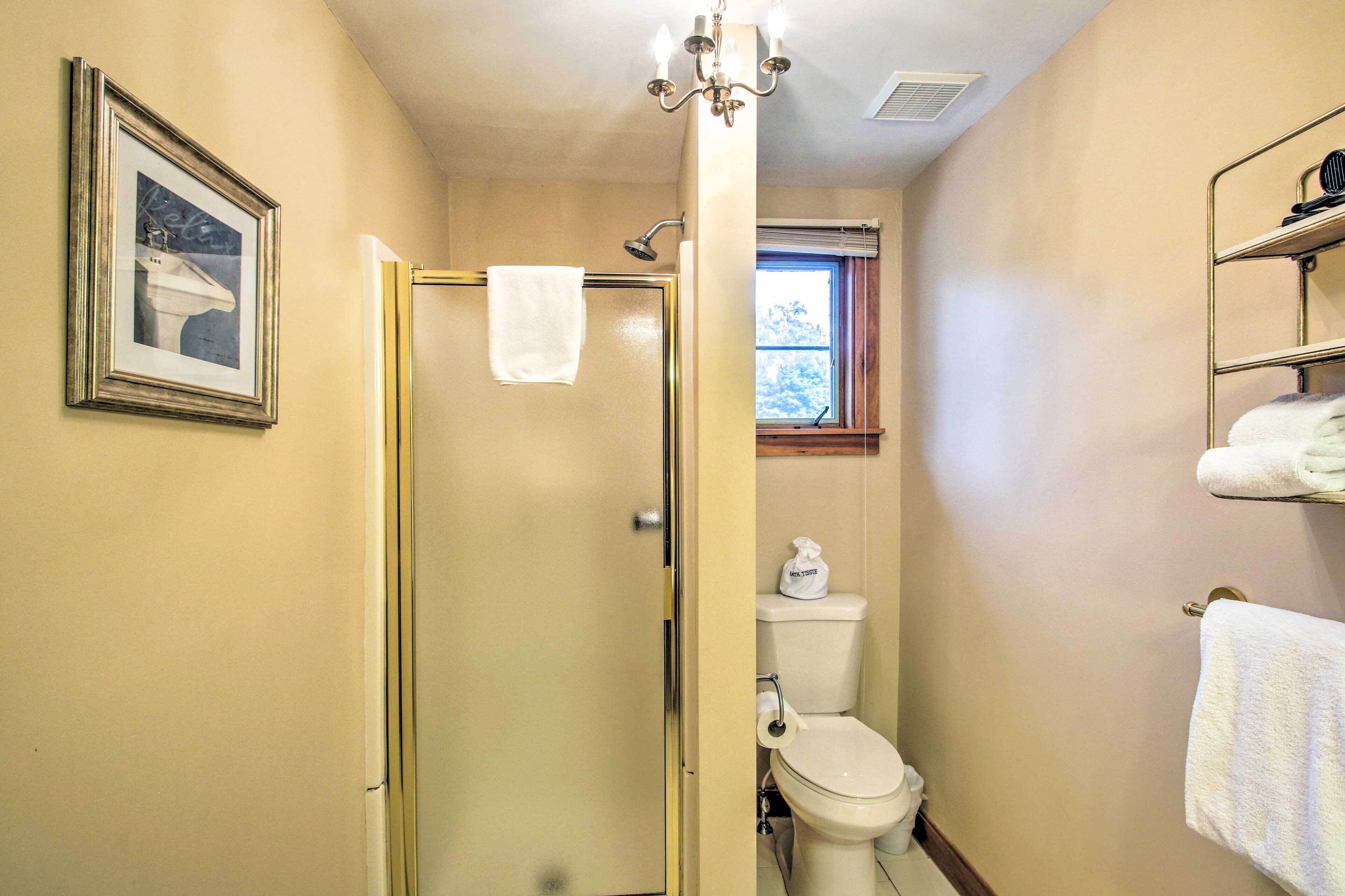 Un baño con ducha, inodoro y ventana.