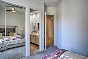 Um quarto com cama, mesa de cabeceira, cômoda e espelho.