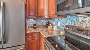 A kitchen with wooden cabinets, a stainless steel refrigerator, a microwave, a stove, and a tiled backsplash. - Golfers Paradise in Myrtle Beach w/ Balcony! (Myrtle Beach)