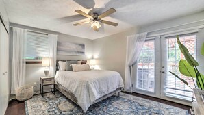 A bedroom with a bed, bedside tables, a ceiling fan, and a large window with blinds. - Pittsburgh Retreat w/ Deck ~ 4 Mi to Dtwn! (Pittsburgh)