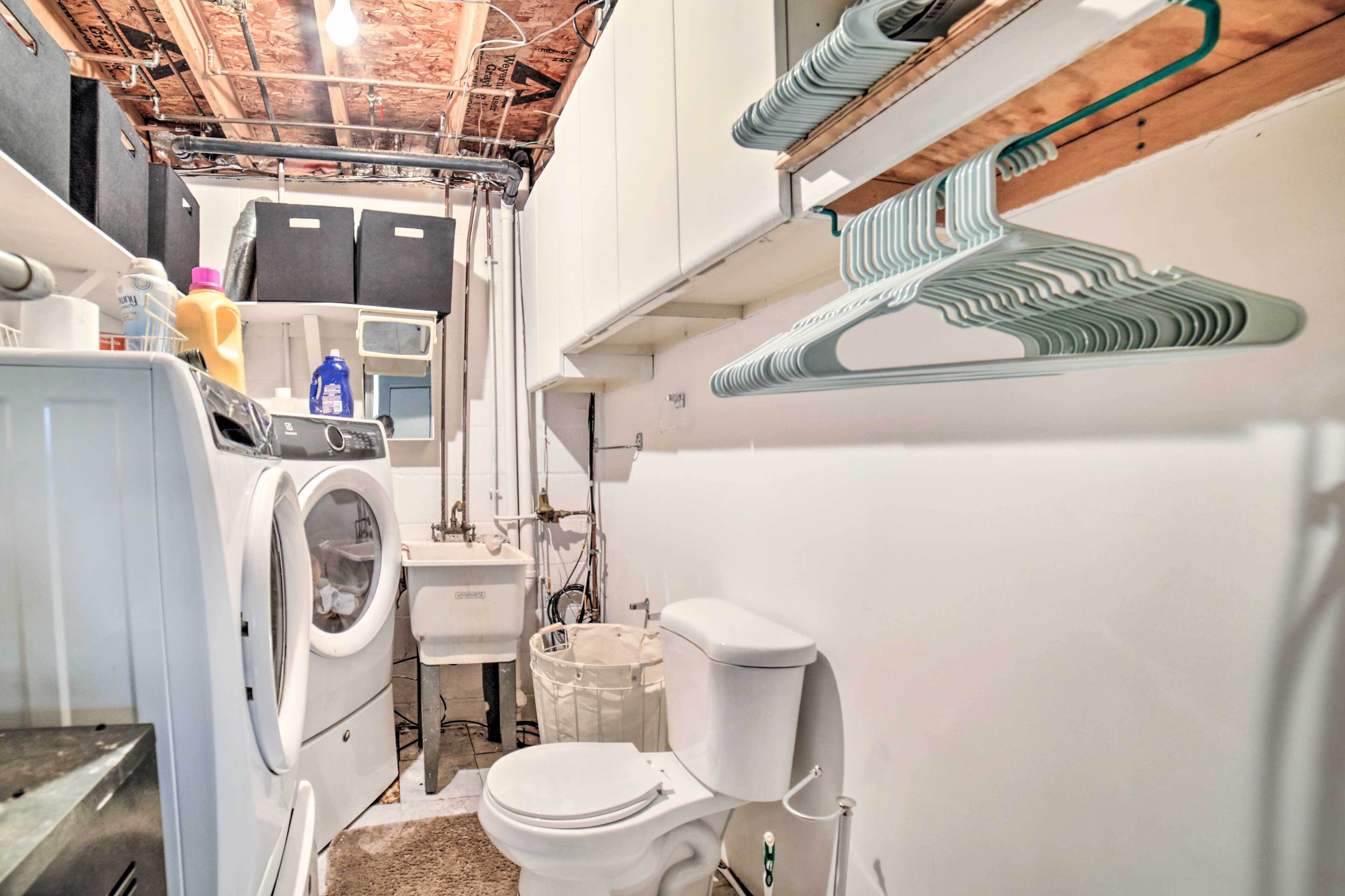 A compact laundry room with a washing machine, a sink, and a toilet.