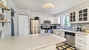 A modern kitchen with white cabinets, stainless steel appliances, and a large island. - Pittsburgh Retreat w/ Deck ~ 4 Mi to Dtwn! (Pittsburgh)