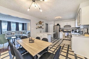 Una cocina moderna con armarios blancos, un refrigerador de acero inoxidable y una cafetera.