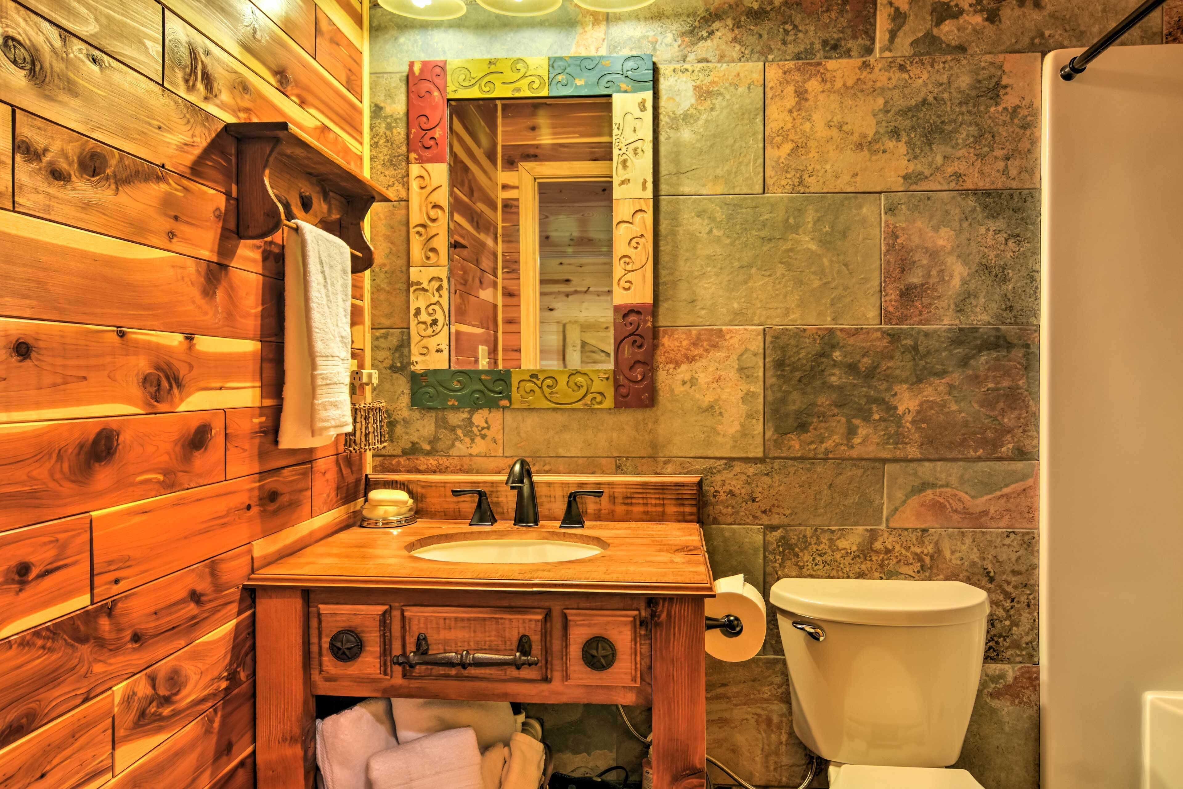 A wooden bathroom with a sink, mirror, and toilet.