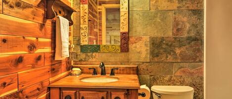 A wooden bathroom with a sink, mirror, and toilet.