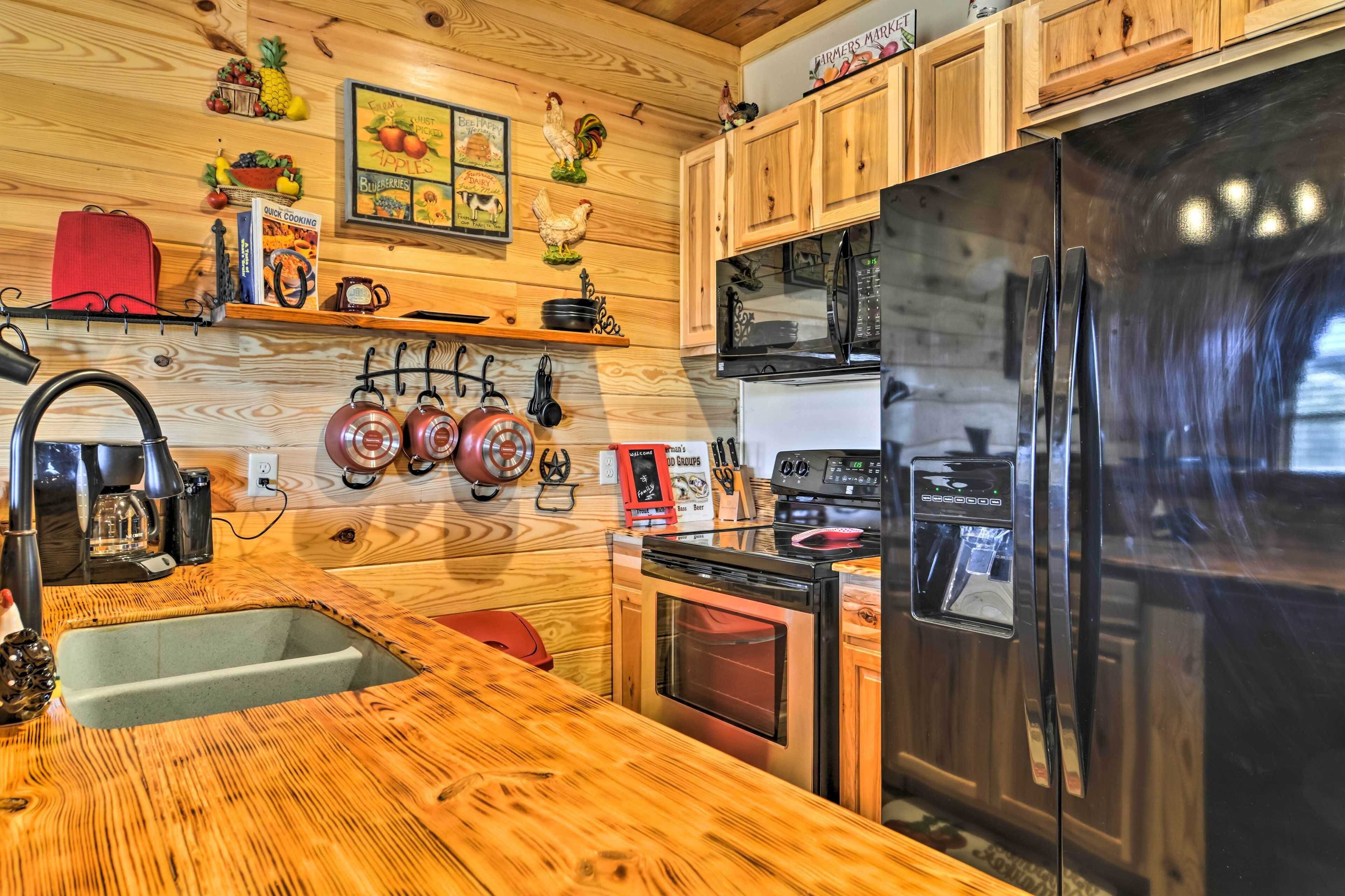 A kitchen with wooden cabinets, a stainless steel refrigerator, a microwave, and a sink.