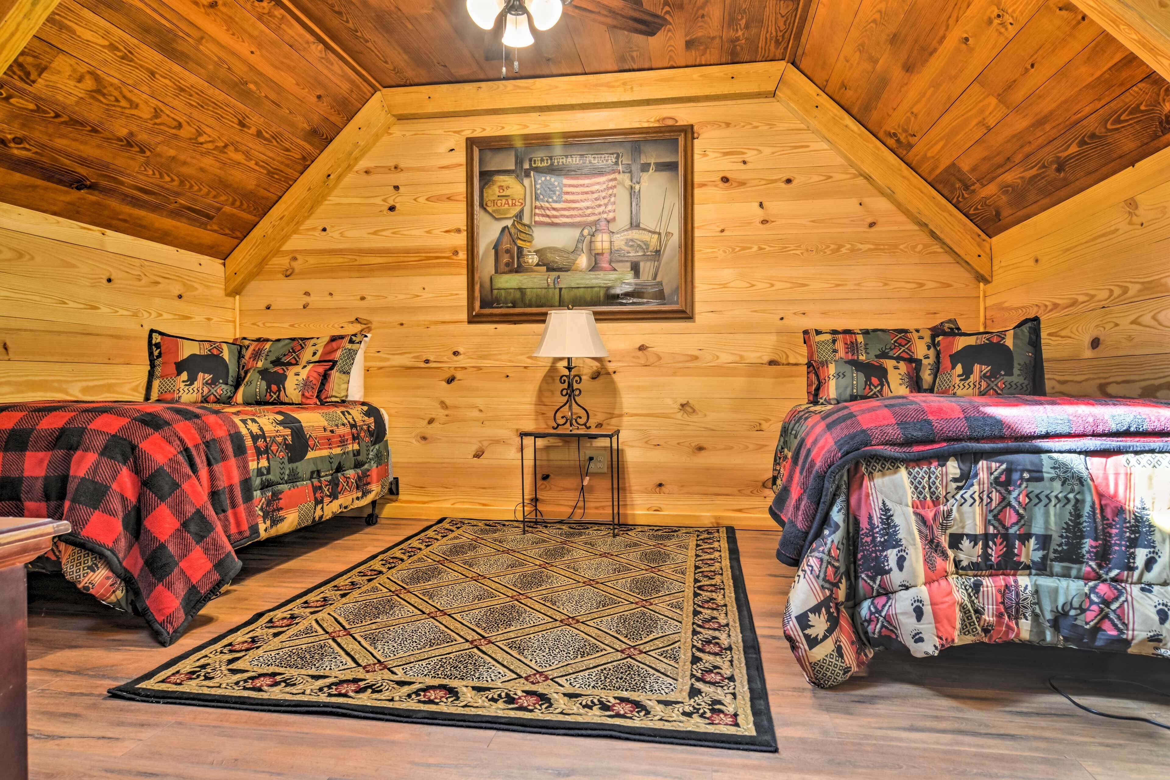 A cozy log cabin bedroom with two beds, a rug, a lamp, and a framed picture on the wall.