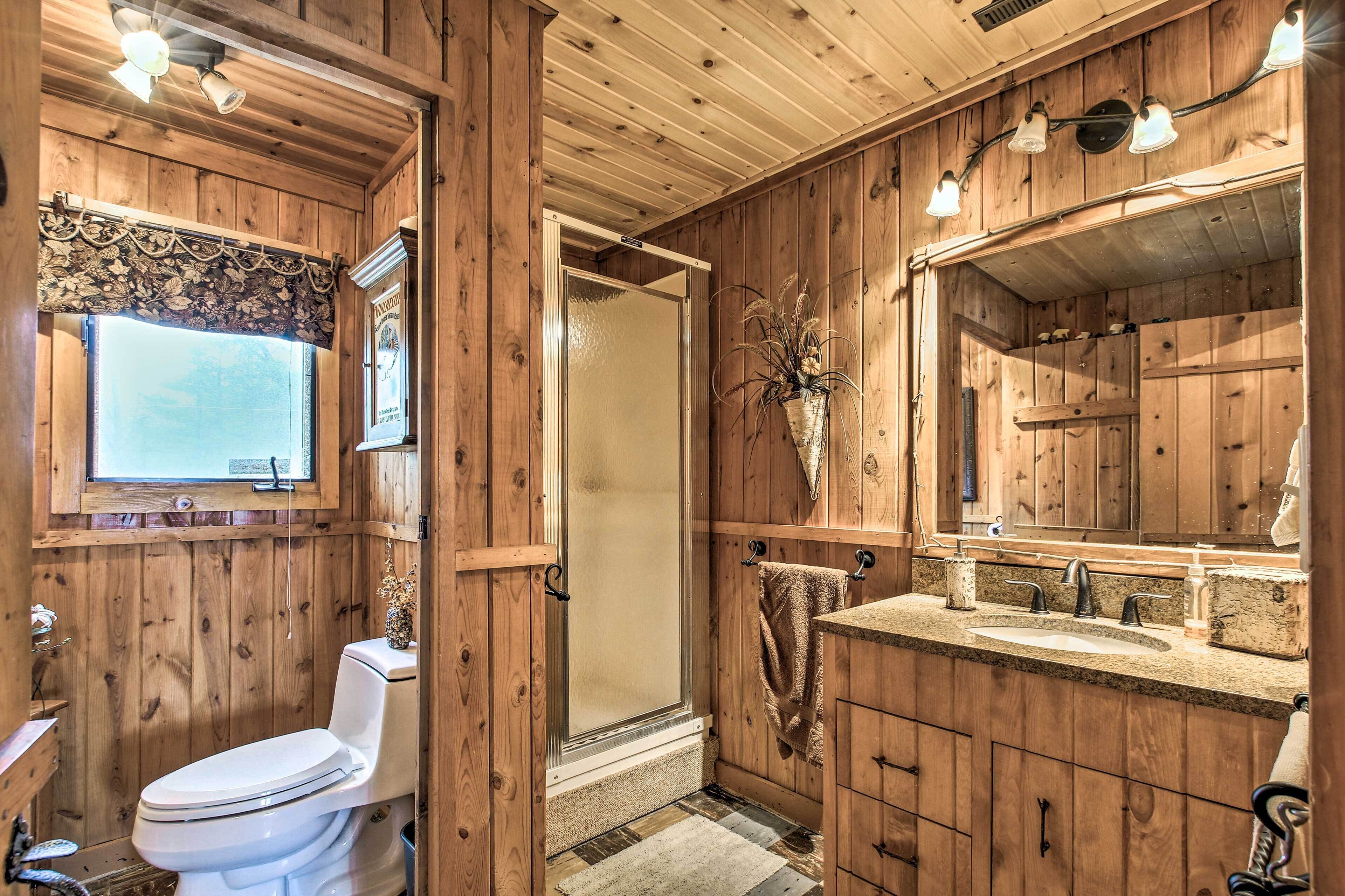 A wooden bathroom with a toilet, sink, and shower.