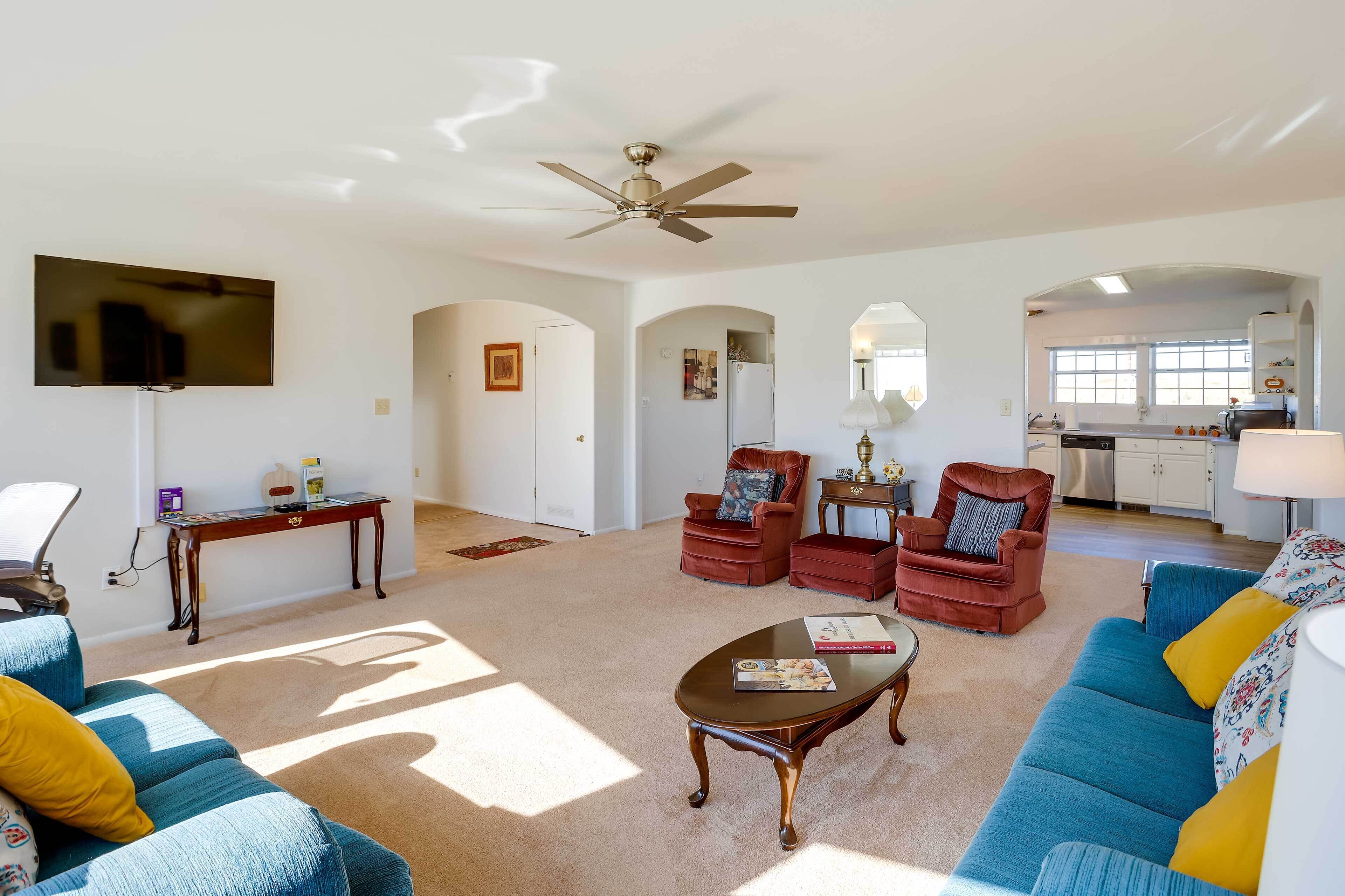 A spacious living room with a ceiling fan, a flat-screen TV, a coffee table, and a sofa.