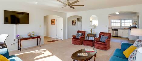 A spacious living room with a ceiling fan, a flat-screen TV, a coffee table, and a sofa.