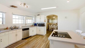 Una cocina moderna con armarios blancos, microondas integrado y una isla central con estufa.