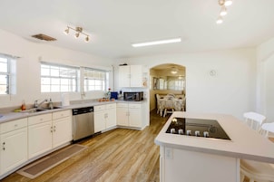 Una cocina moderna con armarios blancos, microondas integrado y una isla central con estufa.