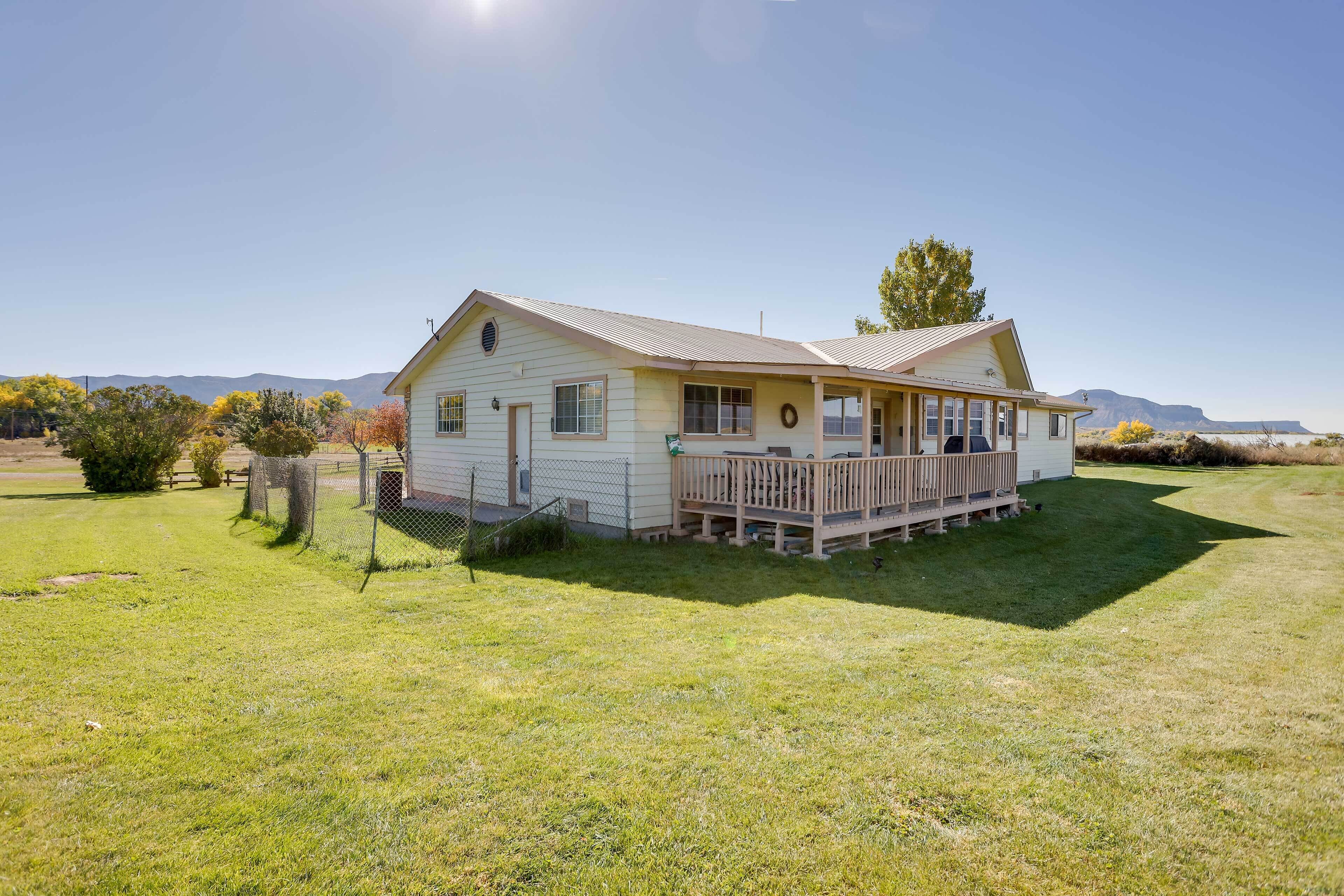 A single-story house with a front porch, a fenced yard, and a mountain backdrop.