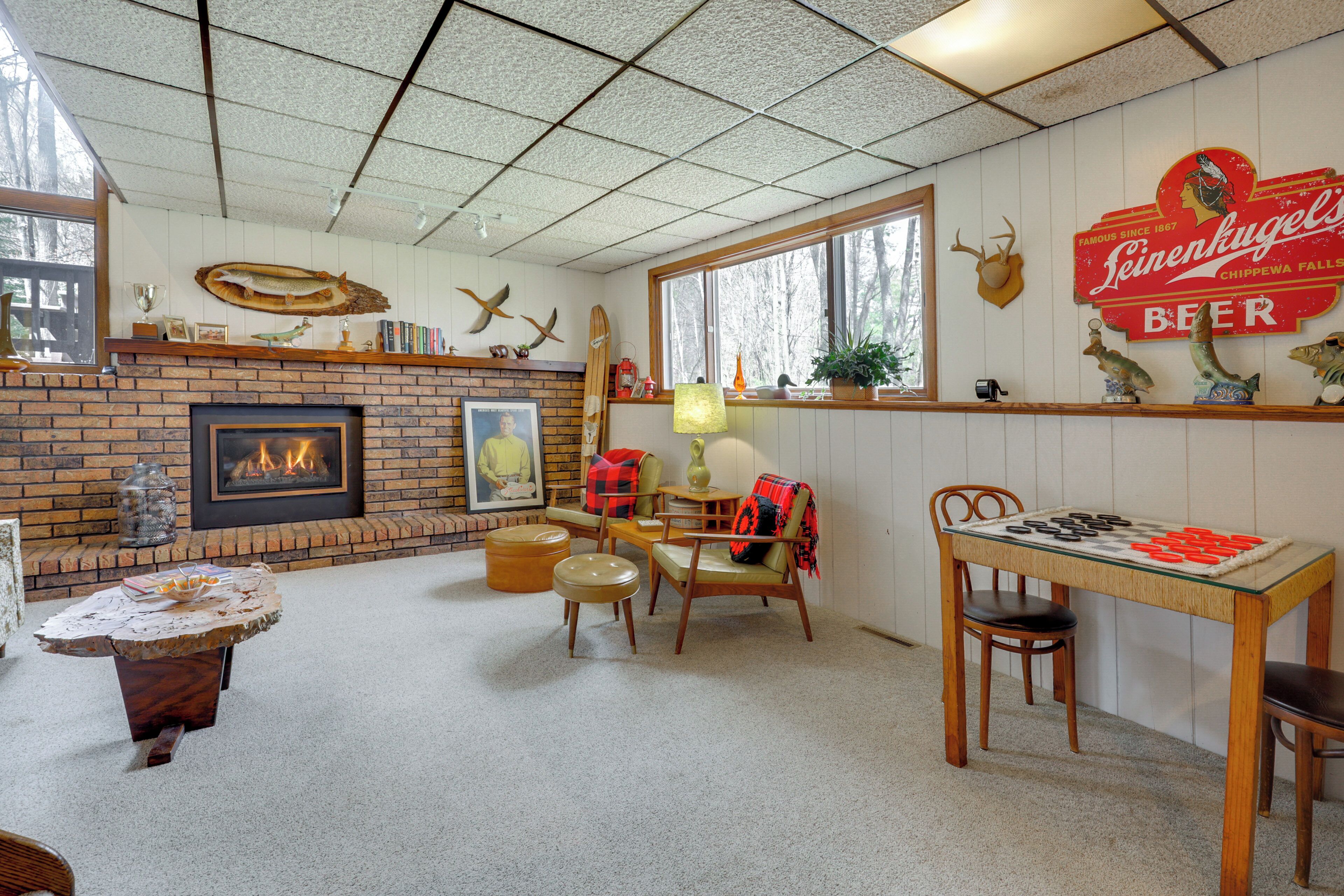 A cozy room with a fireplace, a table with a board game, and a sign for Leinenkugel's Beer.