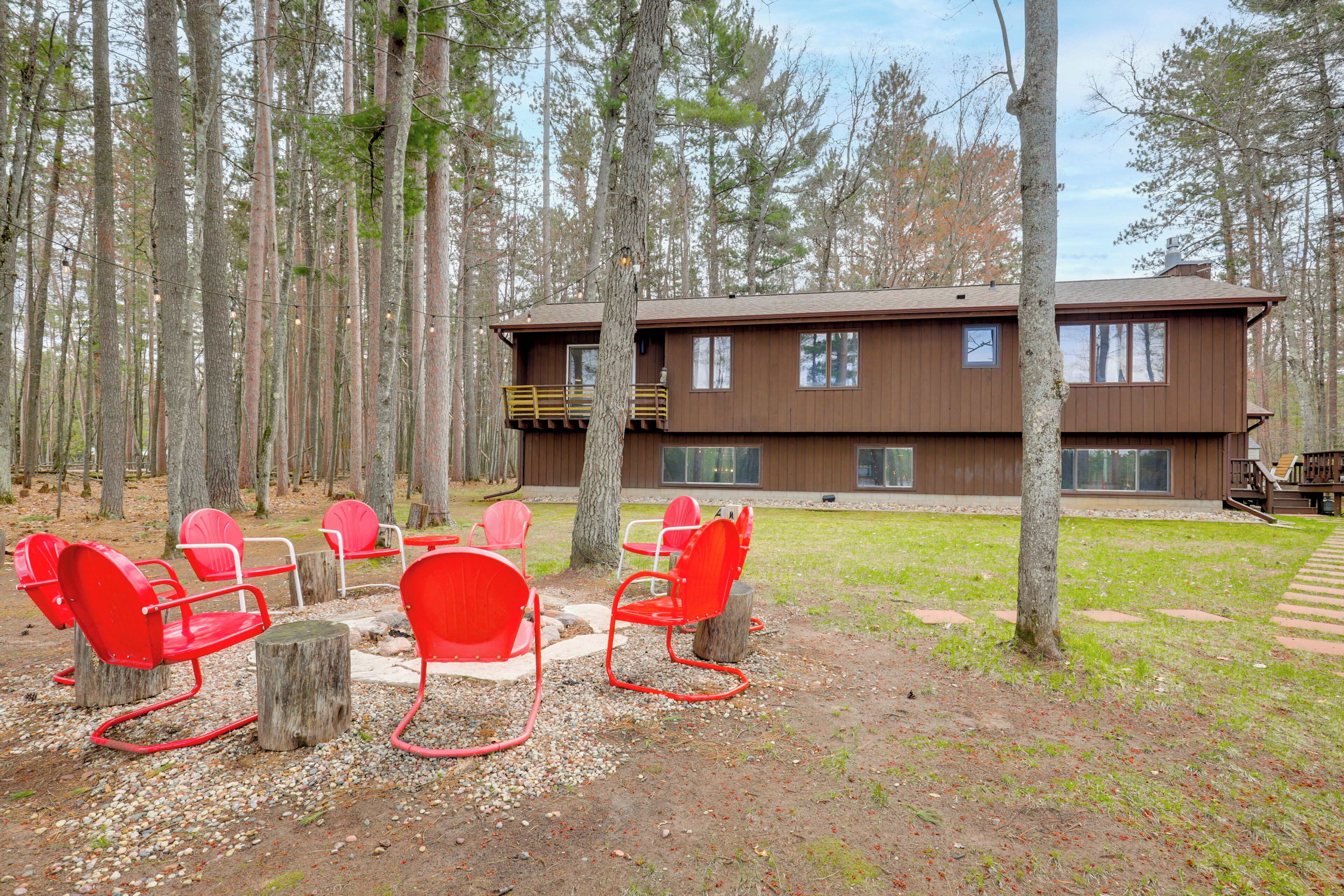 A cabin with a deck, surrounded by a forest.