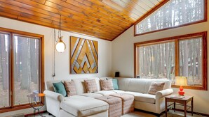 A cozy living room with a sectional sofa, a small table, and a lamp. - Game Room! Mid-century Escape in the Northwoods (Woodruff)